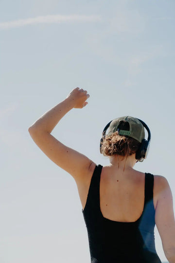 Femme de dos levant le poing librement avec casque audio - sentiment de liberté et d'accomplissement - retraite sortir de sa zone de confort kiffer Les Rayonnantes